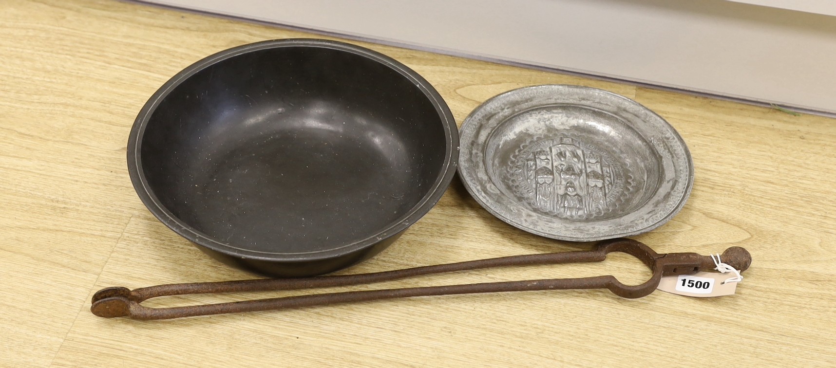 An 18th century pewter dish, an embossed pewter plate and a pair of iron fire tongs